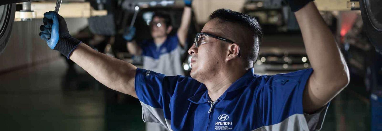 Mecánico en taller Hyundai llevando a cabo revisión a un auto