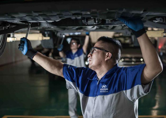 Mecánico en taller Hyundai llevando a cabo revisión a un auto